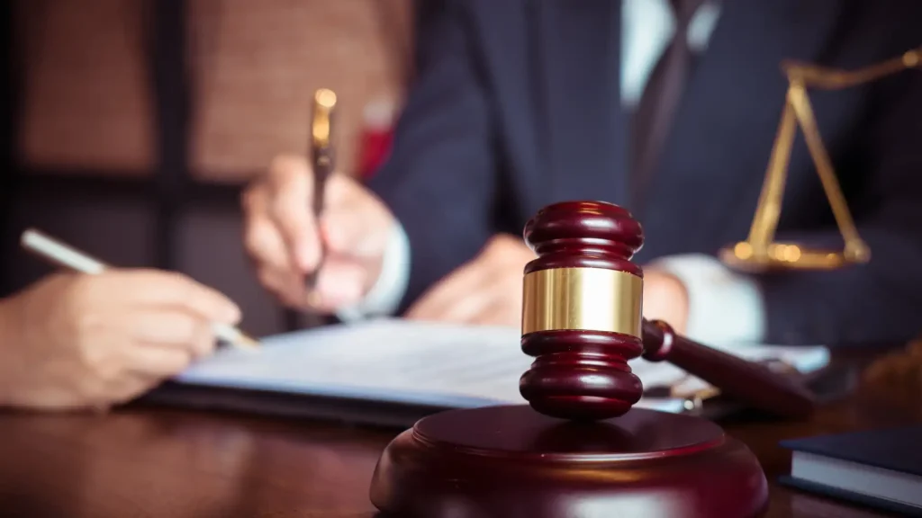 Close-up of a gavel and a person signing a legal document.