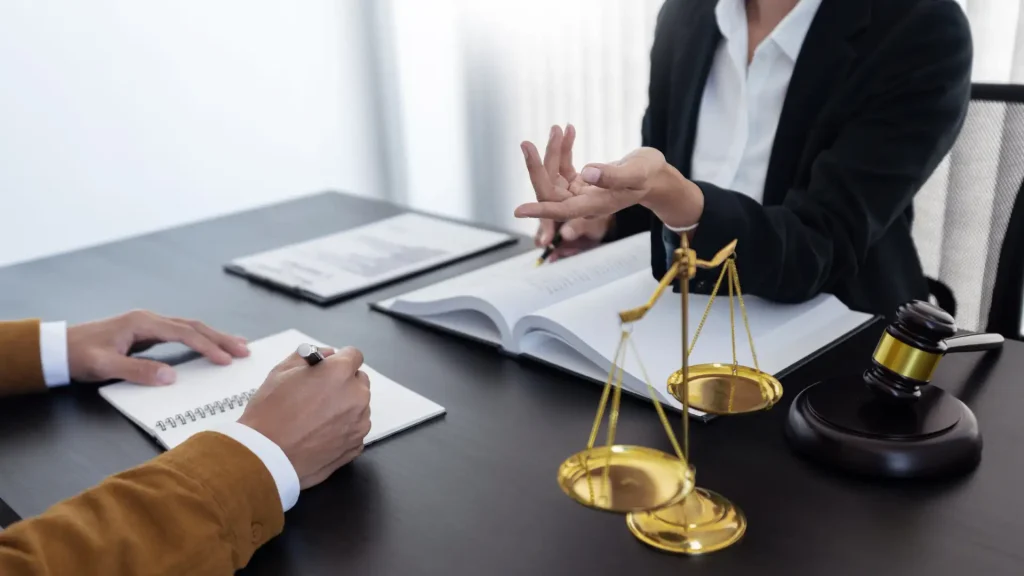 Lawyer discussing legal matters with a client, with scales of justice on the table.
