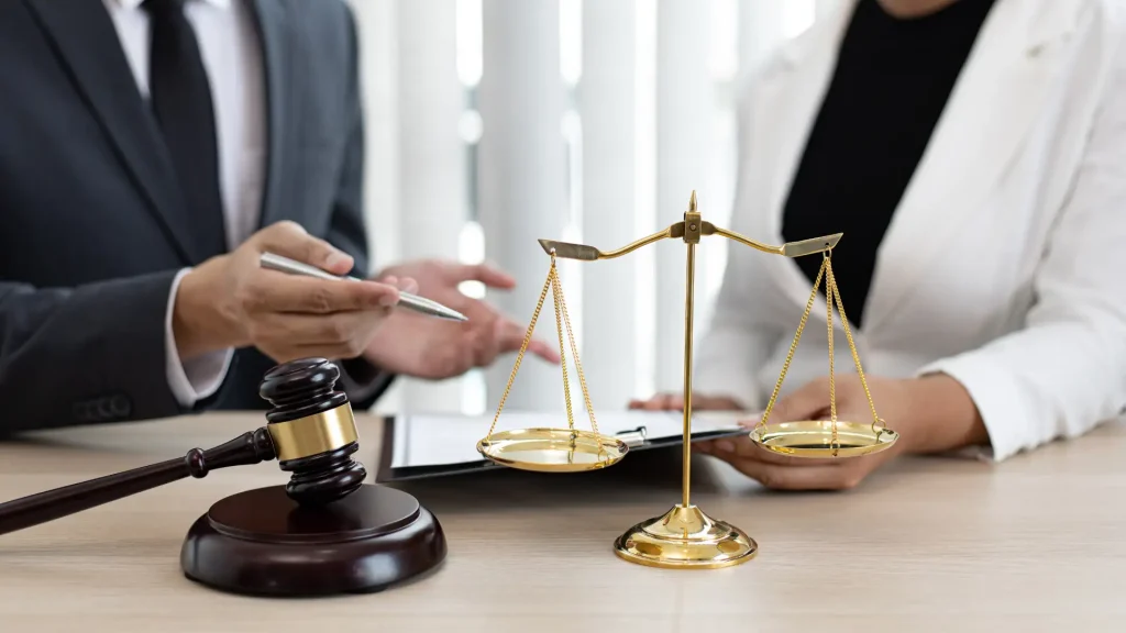Lawyer discussing documents with a gavel and scales of justice on the table.
