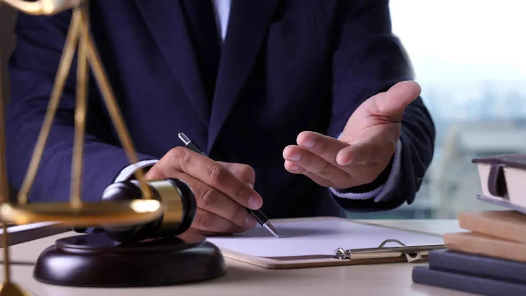 A person signing legal documents with a gavel in the foreground