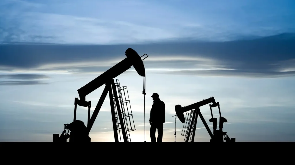 Silhouetted oil pumpjacks and worker at dusk