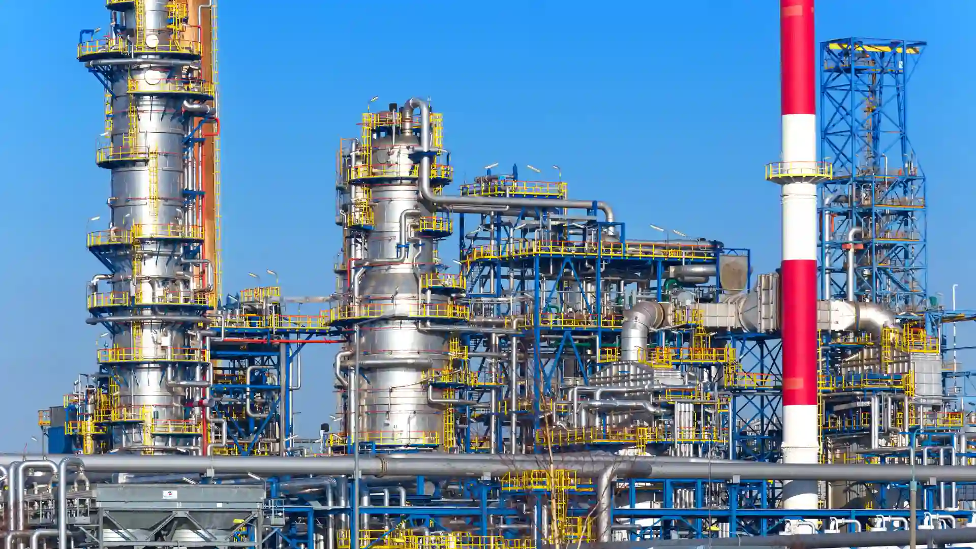 Industrial oil refinery structure with pipes and towers under a clear blue sky