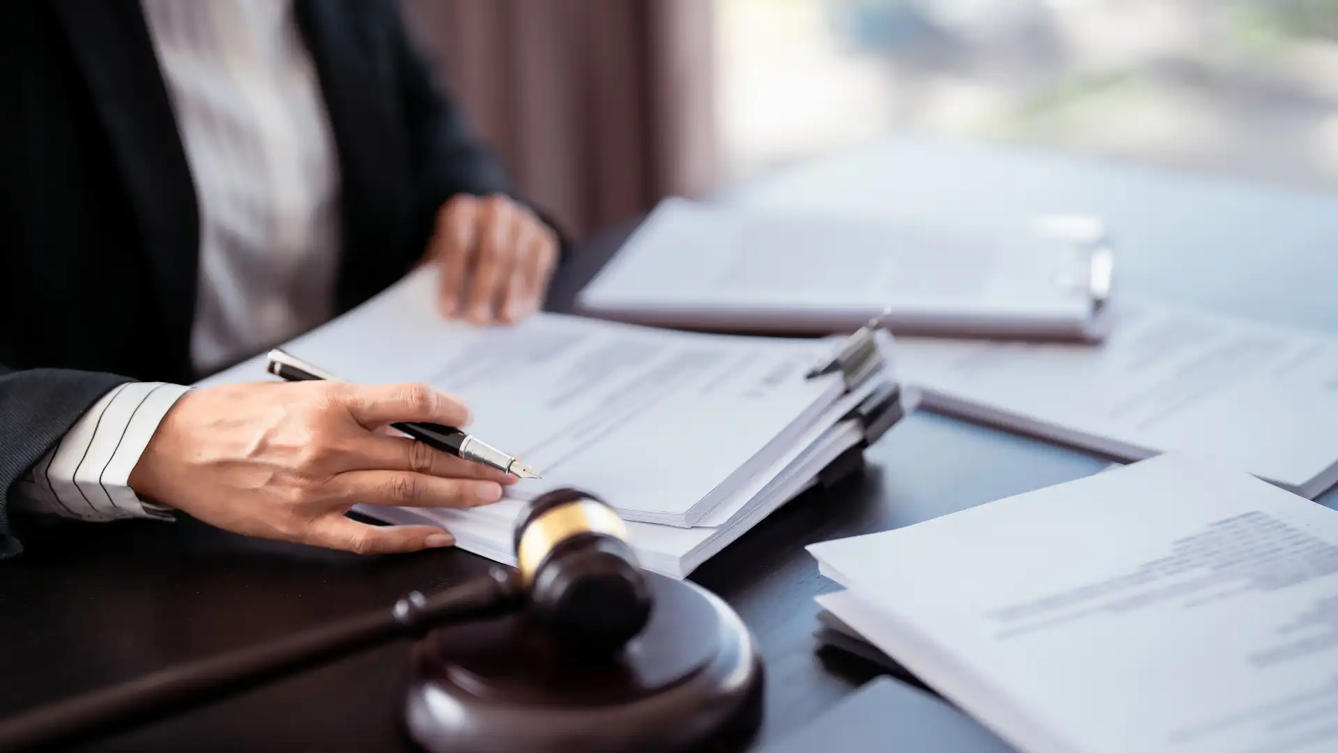 Person reviewing legal documents at a desk with a gavel and stack of papers.